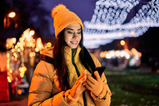 istock woman uses a cell phone at a Christmas bazaar 1290329227