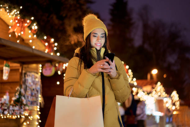 istock woman uses a cell phone at a Christmas bazaar 1290329277