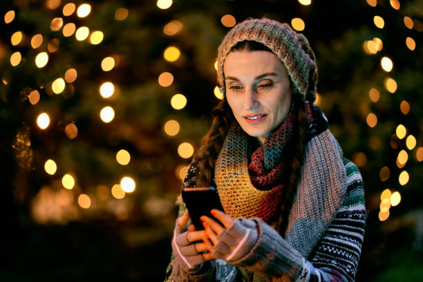 istock woman uses a cell phone at a Christmas bazaar 1290329279