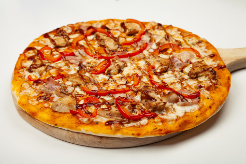 Delicious pizza with bacon and chicken Teriyaki served on a wooden plate, ingredients Signature sauce, mozzarella cheese, Teriyaki chicken, bacon, Bulgarian pepper, Teriyaki sauce on white