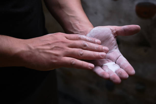 Close up of a climber man using liquid chalk magnesium Close up of a climber man using liquid chalk magnesium preparing to climb indoor. sports chalk stock pictures, royalty-free photos & images