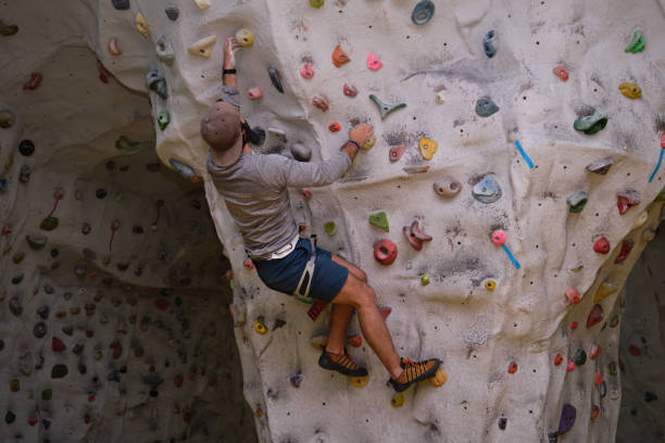 istock Active sporty man wearing protective face mask and a hat practicing rock climbing on artificial rock in a climbing wall 1290332046