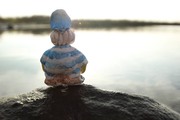 Clay figure of an sailor on a mossy rock at the lake admiring the views