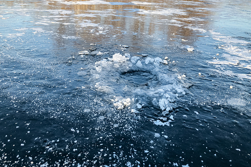 Frozen hole for ice fishing in the lake ice