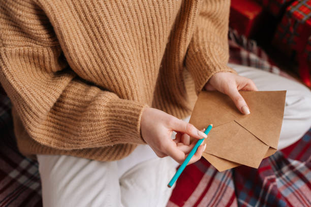 istock Close-up hands of unrecognizable young woman holding empty envelope and pen preparing writing letter 1290335979