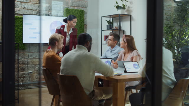 Office Conference Room Meeting: Female Chief Executive Talking to a Diverse Team of Professional Businesspeople. Creative People Listen to CEO Discuss Design, Data Analysis, Plan Marketing Strategy