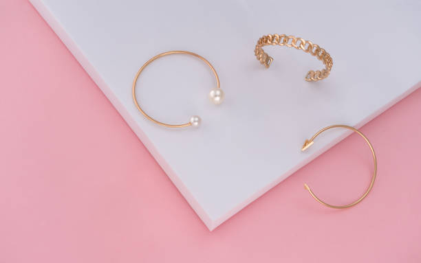 istock Three golden bracelets on pink and white paper background with copy space 1290338350