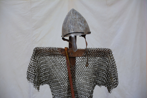 Mannequin clothed ancient helmet and chain armour on white background