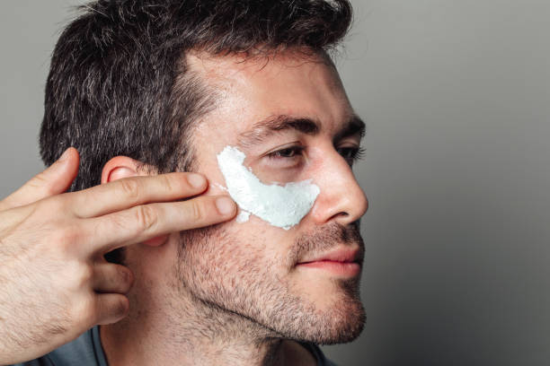 istock Handsome Young Man Applying White Face Mask Underneath his Eyes 1290344069