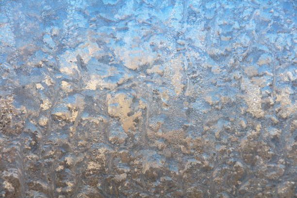 Frost drawing on window glass, snowflake ornament after anomaly ice cold. Blue top view. High quality photo
