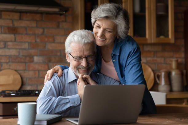 istock Smiling mature couple hugging, using laptop in kitchen together 1290347063