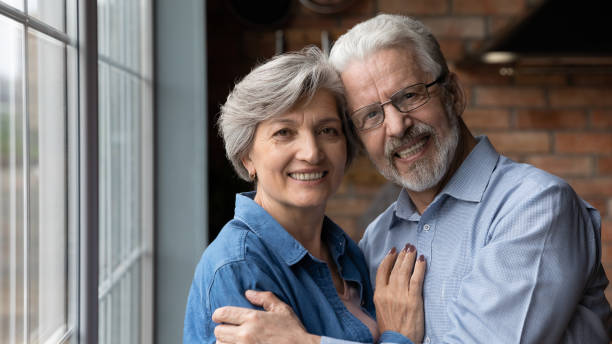 istock Head shot portrait smiling mature couple hugging, looking at camera 1290347075