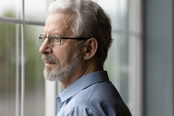 istock Close up thoughtful upset mature man looking out window 1290347081