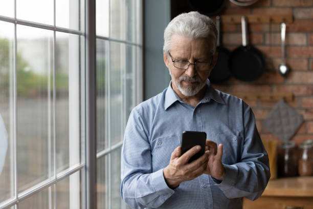istock Close up satisfied mature man wearing glasses using phone 1290347095