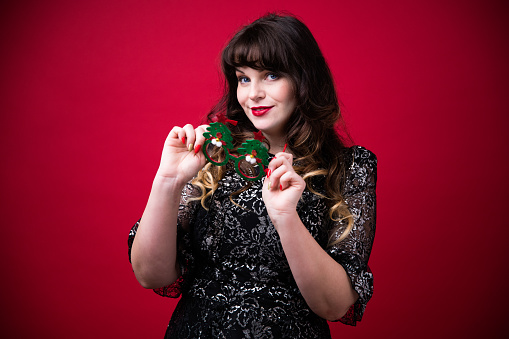 Stylish woman in black dress holding xmas tree shaped sunglasses.