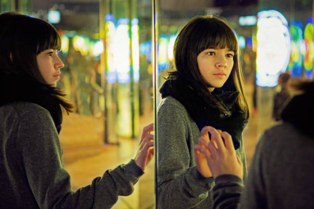 Depressed young girl is looking herself in a mirror