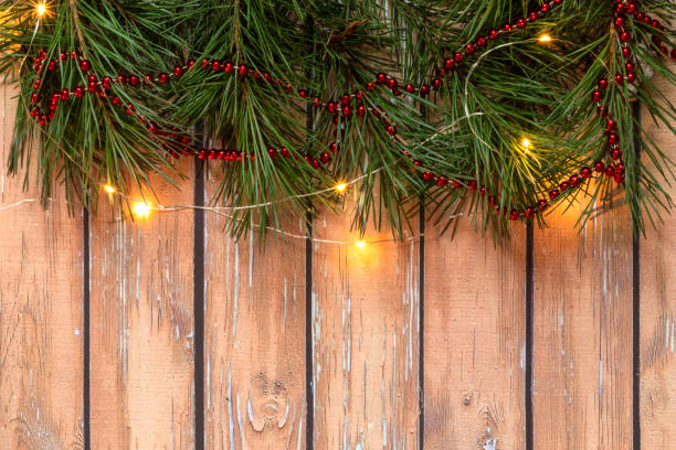 istock Christmas composition with pine branches, red beads, with lights at the top on a wooden background. Christmas concept. Selective focus. Top view. 1290355574