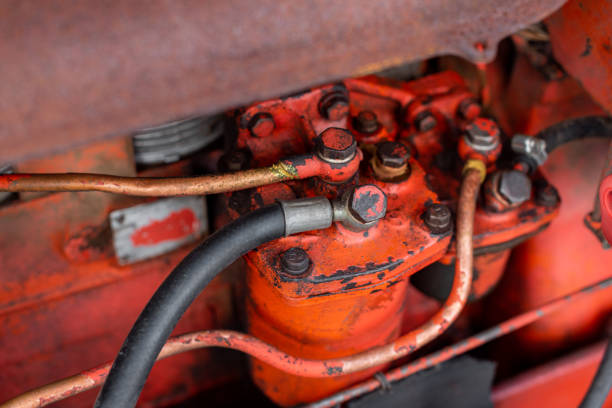 Bolts and wires on red rusty tractor abstract closeup with sharp selective focus grease oil vivid color detail autumn harvest