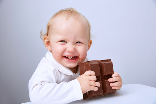 Baby eats a large bar of chocolate. Copy space.
