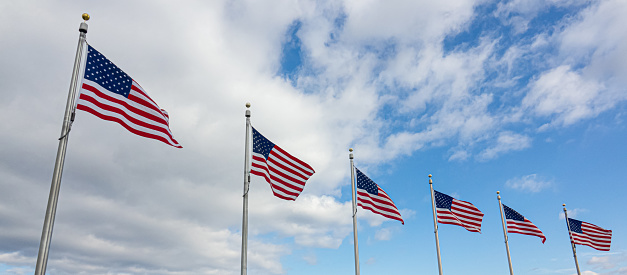 Six waving flags of USA on sky and clouds background. Banner wide photo.