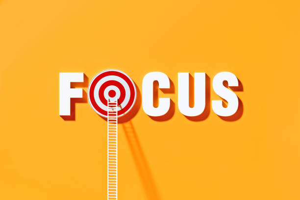 istock White Ladders Leaning on Focus Written  Bull's Eye Target on Yellow Wall 1290369629