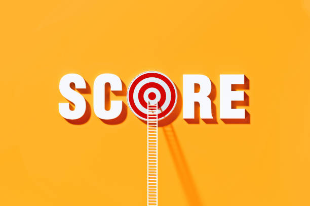 istock White Ladders Leaning on Score Written  Bull's Eye Target on Yellow Wall 1290369998