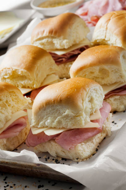 istock Preparing Baked Ham And Swiss Sliders on White Tray Buns 1290371434