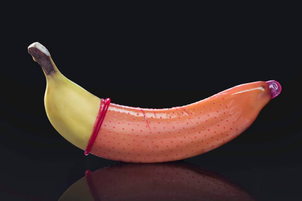 banana with condom, studio fresh banana with red condom on a black background, studio condom photos stock pictures, royalty-free photos & images