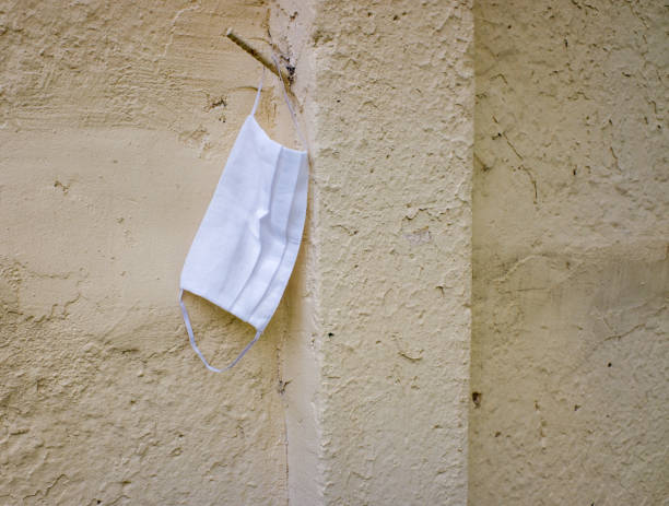 istock a white protective mask hangs on an old beige wall 1290380523