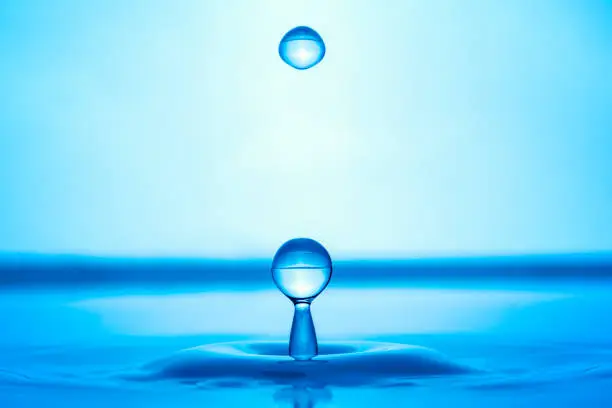 Photo of Water drop splashing into blue water surface