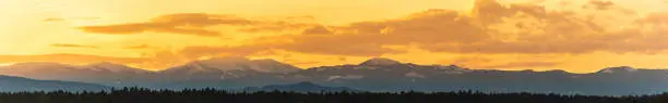 Styrian alps covered with snow in orange light of sunset. View at mountain chain of Lavanttaler Alps. Background or banner