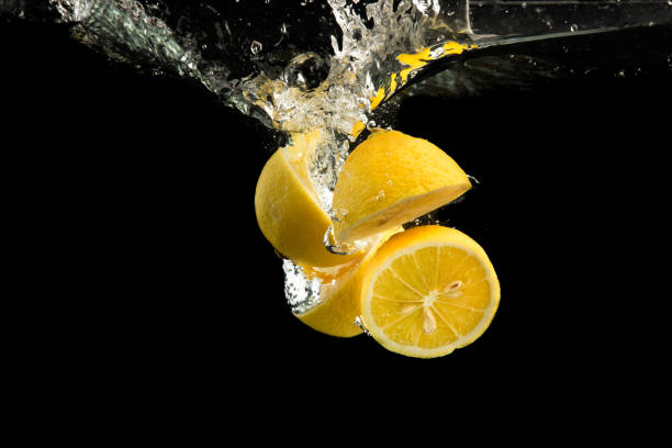 istock Fresh yellow lemons in water splash on black background 1290383416