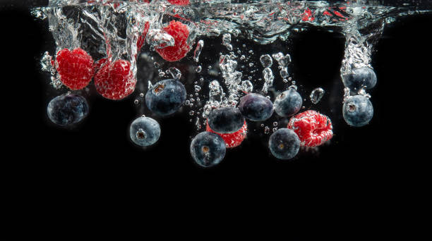 istock Blueberries and raspberries splashing into crystal clear water with air bubbles and sinking 1290383425