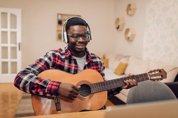 istock Young African-American man attending an online guitar class 1290390995