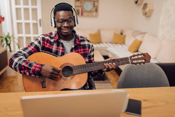 istock Afro man learning to play guitar online at home 1290391007