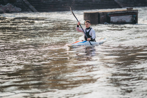 jeune homme musculaire pendant l’entraînement de sprint de kayak sur l’eau immobile - skiff photos et images de collection