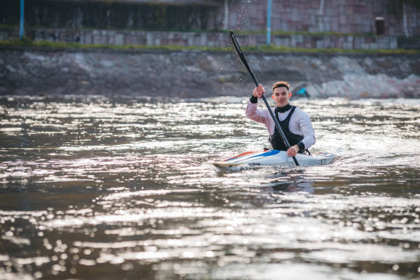 jeune homme musculaire pendant l’entraînement de sprint de kayak sur l’eau immobile - skiff photos et images de collection