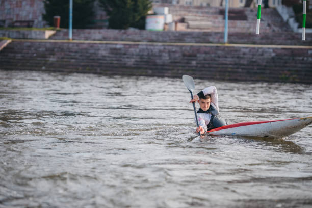 jeune homme musculaire pendant l’entraînement de sprint de kayak sur l’eau immobile - skiff photos et images de collection