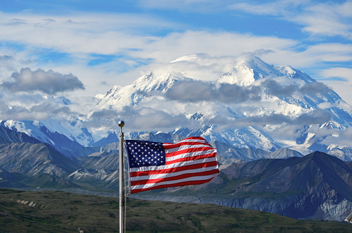 U.S. flag flying in front of the tallest mountain on the North American continent, Denali.  Denali National Park and Preserve, Alaska.