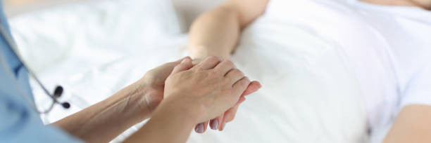 istock Doctor holds lying patient by hand closeup 1290442479