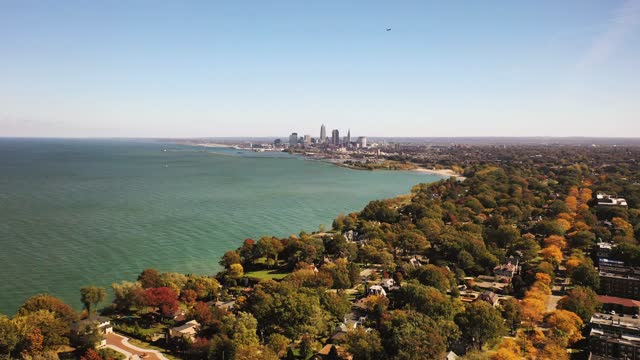 Beautiful rising up aerial panoramic view of Cleveland, Ohio from a residential neighborhood with the downtown skyline and water of Lake Erie on the horizon on a sunny blue sky autumn day.
