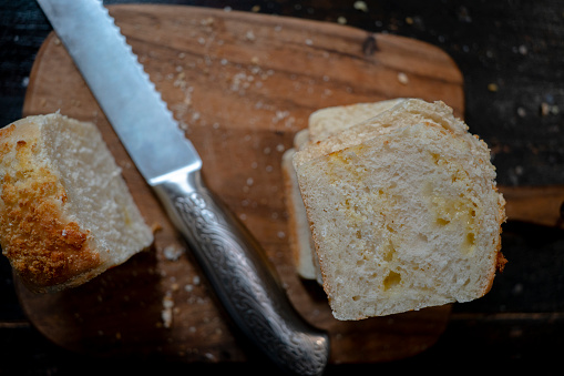 slices of homemade coconut milk loaf, bread slicer and cutting board on table