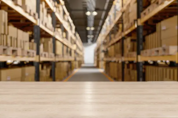 Photo of Wood Table In The Warehouse With Blur Background And Cardboard Boxes On The Rack.