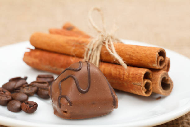 istock Chocolate candy on white plate with cinnamon and coffee beans. 1290447636