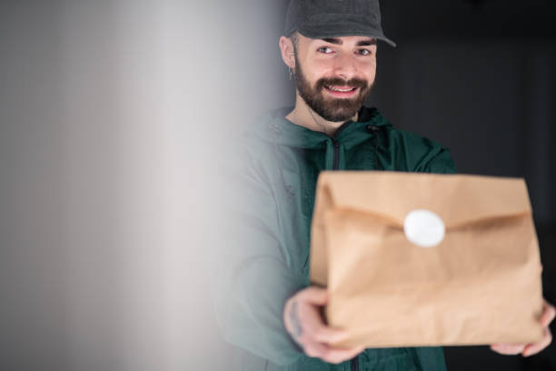 istock Smiling and delivering take out in sealed paper bag 1290451488