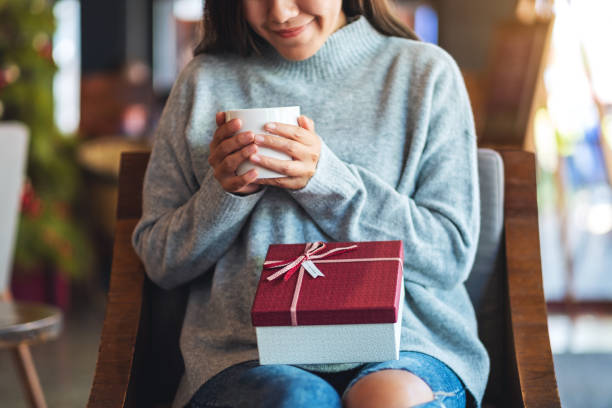 istock a beautiful young woman holding a gift box while drinking coffee 1290451808