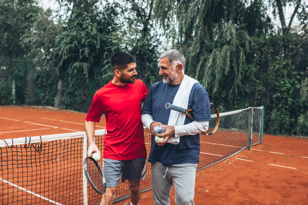 father and son spending time together playing tennis - tennis active seniors healthy lifestyle senior men imagens e fotografias de stock