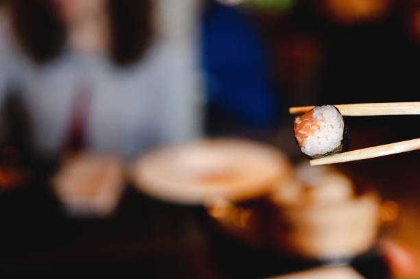 istock Copy space close-up traditional Japanese sushi uramaki roll with salmon between chopsticks. 1290456879