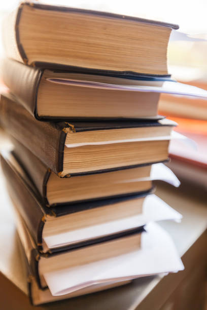 istock Vertical shot of stacked books with bookmarks and notes on the table 1290460775