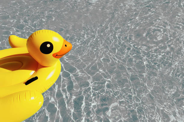 pato inflable amarillo brillante en agua azul ondulada en la piscina. - colores fotos fotografías e imágenes de stock